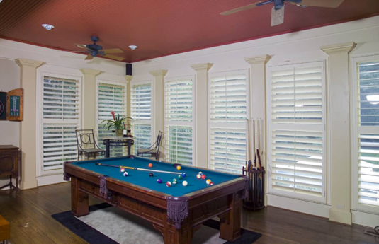 pool table in a room with plantation shutters